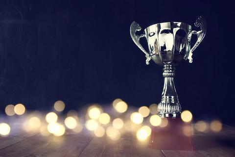 image of trophy over wooden table and dark background, with abstract shiny lights